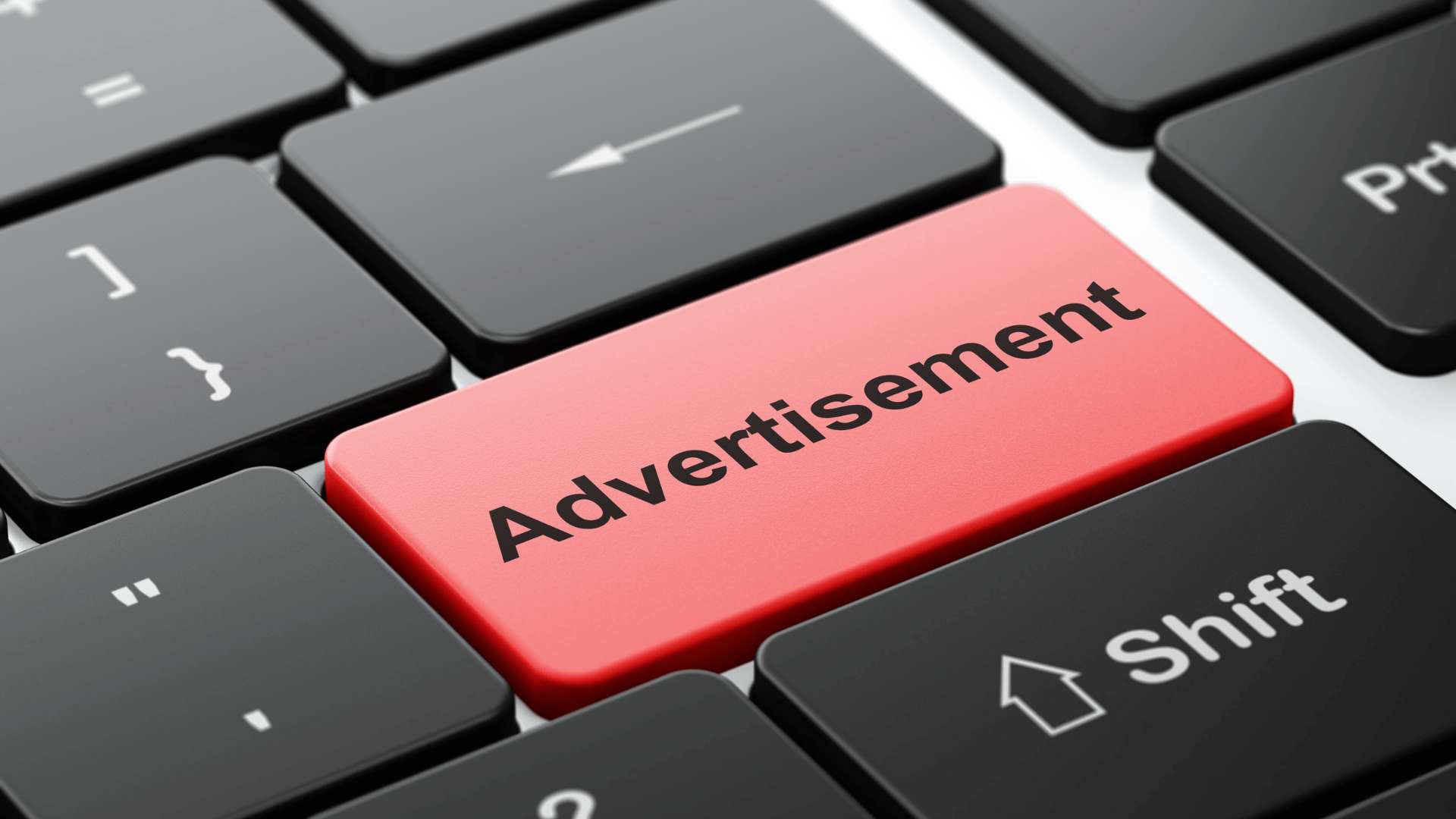 La tastiera di un computer con i. tasti neri tranne uno che è rosso e con scritto Advertisement 