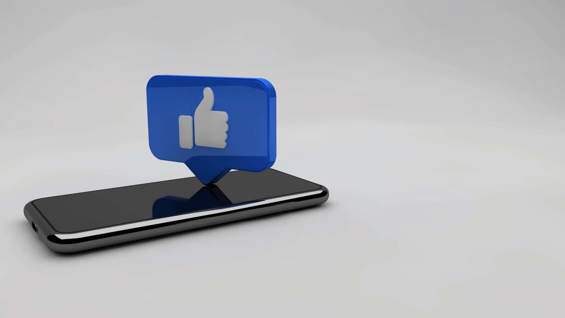 Un telefono appoggiato su uno sfondo bianco con l'icona del like blu che emerge dallo schermo