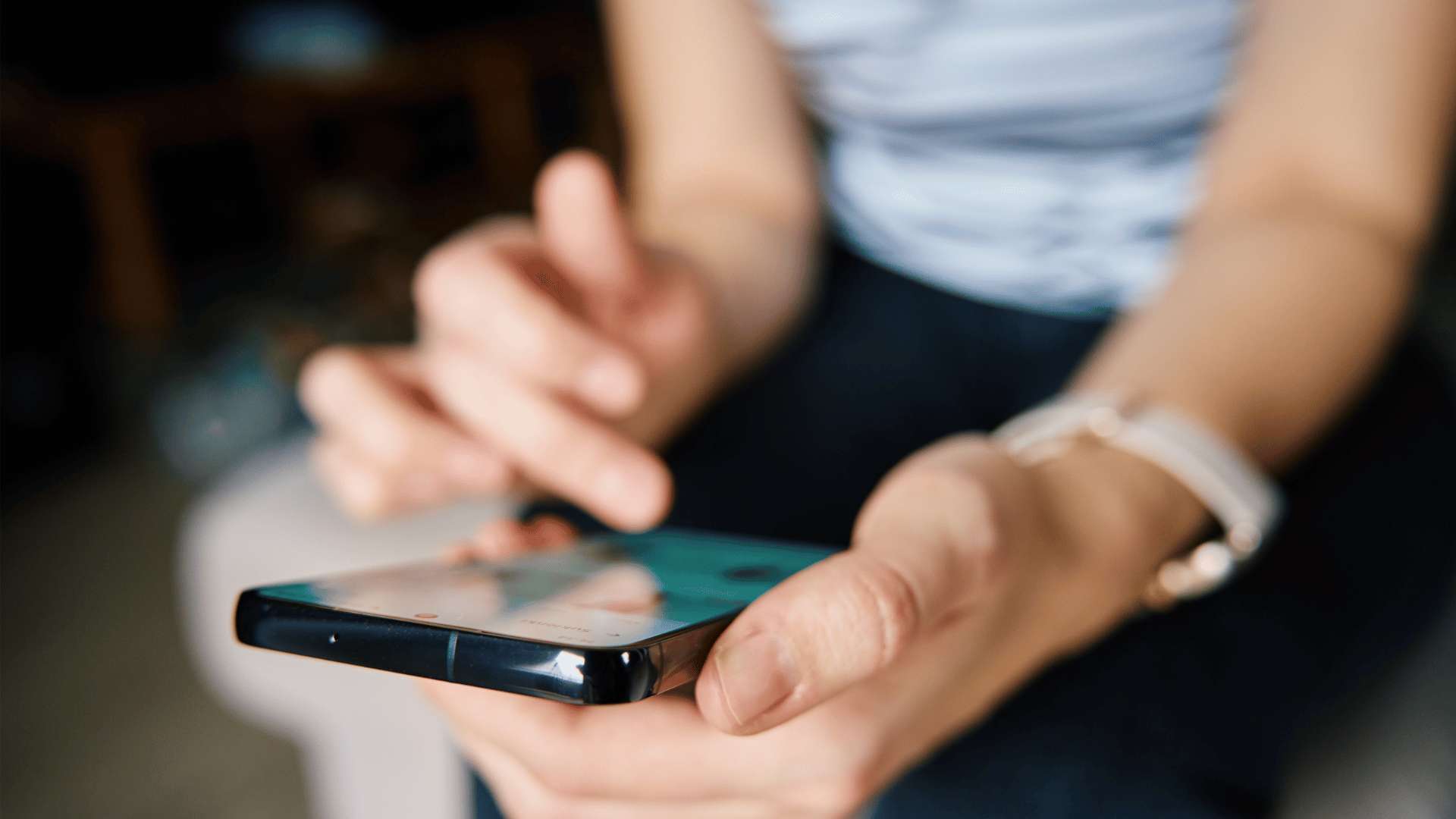 Primo piano di mani e braccia che reggono uno smartphone