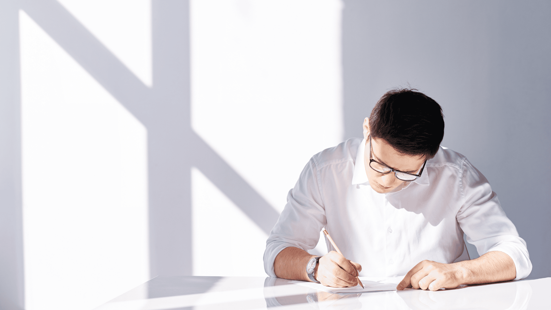 Una persona vestita di bianco scrive con una matita su un foglio