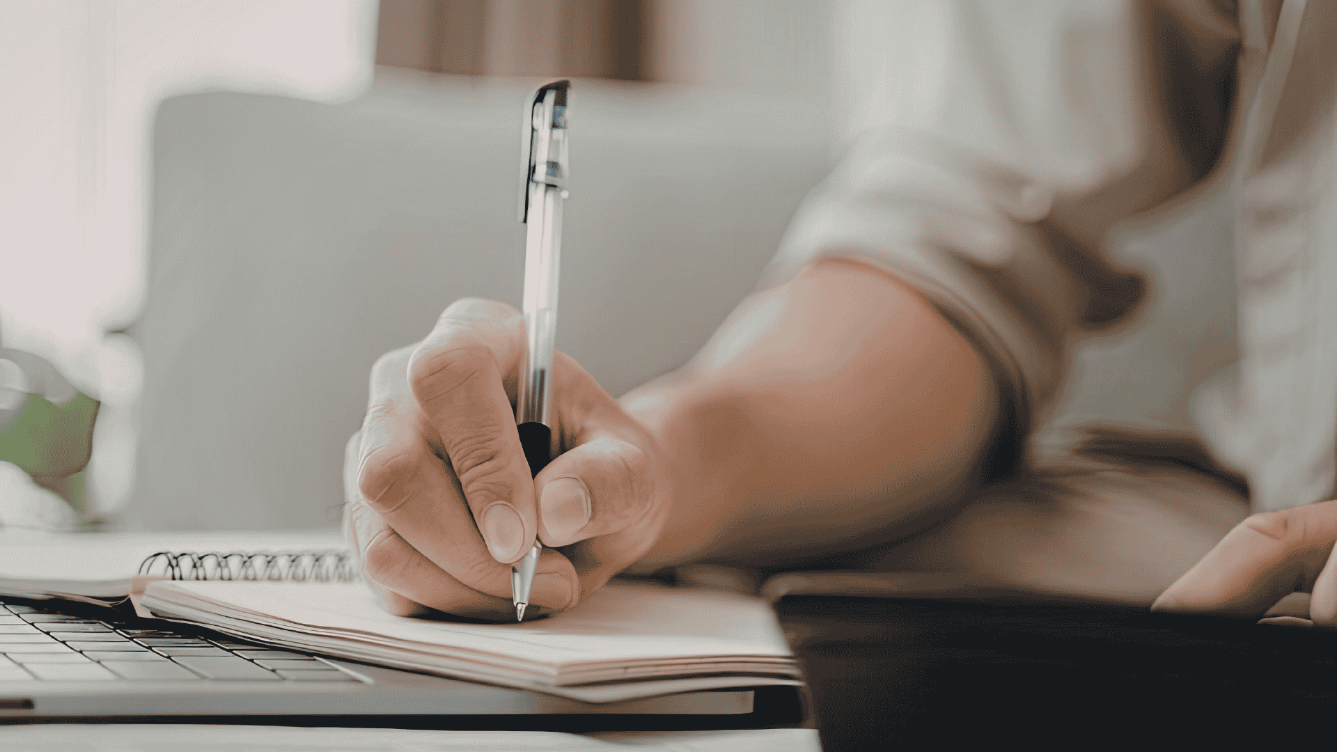 Una persona scrive a penna su un quaderno